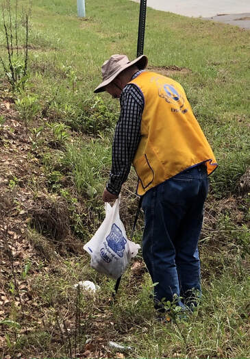 Picture of a Local Lion picking up trash on a project to help keep their community clean!